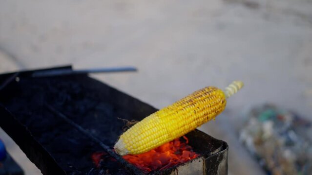 Cooking corn on a fire, Close-up, Hands hold a cob of corn, Slow motion