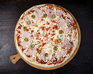 pizza with ham, olives and cheese on wooden plate
