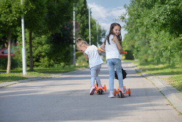 Two little sisters riding their scooters