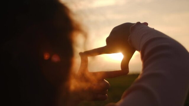 Silhouette of little girl kid making frame gesture with amazing beautiful sunset. Preteen child capturing sunrise. Copy space for promotion content. Imagination, vision, strategy and dream concept