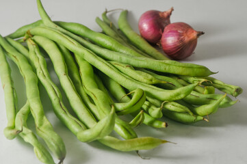 Some green beans and two red onions isolated on a white background