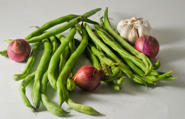 Some green beans and a garlic bulb, three red onions isolated on a white background