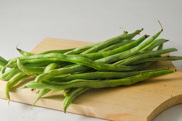 Some green beans on a wooden cutting board isolated on a white background
