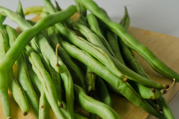 Some green beans on a wooden cutting board isolated on a white background