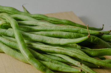 Some green beans on a wooden cutting board isolated on a white background