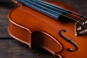 Violin, details of a beautiful violin on rustic wood, low key style photo, black background, selective focus.