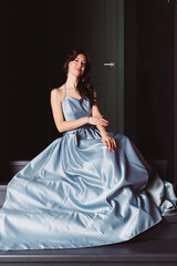 A beautiful girl in a long blue Elegant Exquisite Evening Dress.
