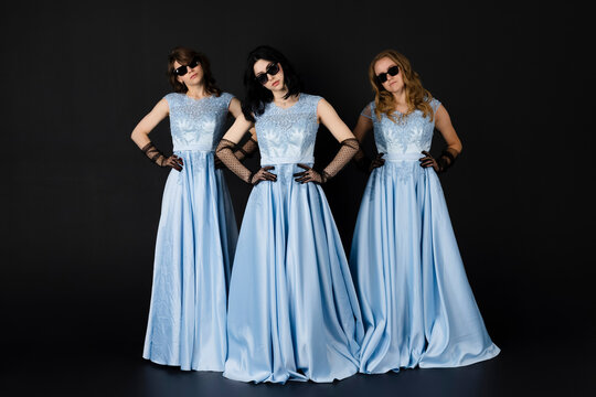 Group Of Three Bridesmaids In Blue Dresses And Black Sunglasses, Posing. Isolated On Black Background.