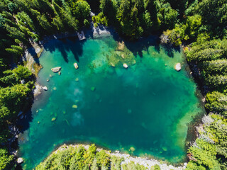 Aerial view of an amazing transparent blue lake with pines