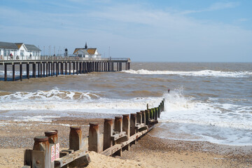 Waves hitting the groynes on Southwold beach with the pier in the background.