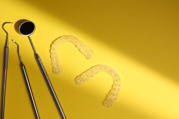 Transparent plastic aligners and dentist's tools on a colored background
