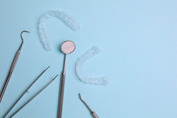 Transparent plastic aligners and dentist's tools on a colored background