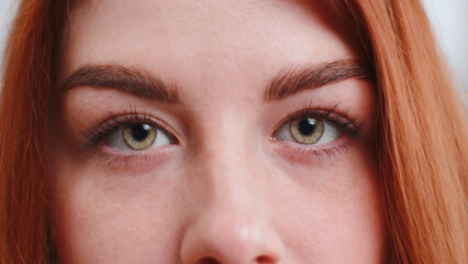 Fototapeta premium Extreme close-up macro portrait of smiling young woman freckles face. Redhead girl eyes, looking at camera. Green eyes of ginger lady. Portrait of teenager positive female opening wide her closed eyes