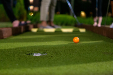 Orange golf ball on a mini golf course. Intentional blur.