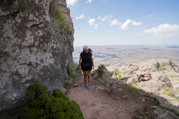 Naklejka na ściany i meble Woman hiking along a foot trail high in the rocky mountains. 