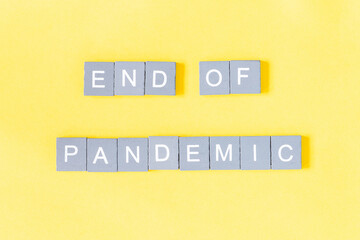 Phrase End of pandemic, gray wooden letters on yellow background