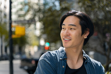 Closeup portrait of attractive smiling asian man looking away standing on the street, copy space