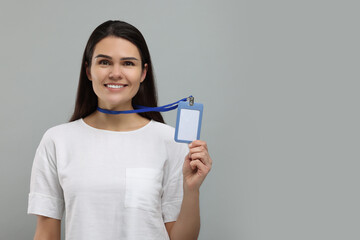 Happy woman holding vip pass badge on grey background, space for text