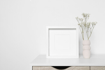 Empty photo frame and vase with dry decorative gypsophila flowers on white table. Mockup for design