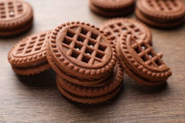 Tasty chocolate sandwich cookies with cream on wooden table, closeup