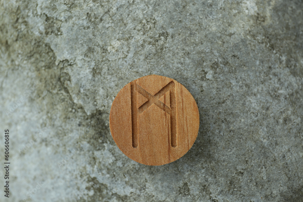 Wall mural Wooden rune Mannaz on stone outdoors, closeup