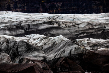 Glacier erosions in Iceland with black volcanic dust on the ice