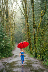 Woman runner with red umbrella in a forest