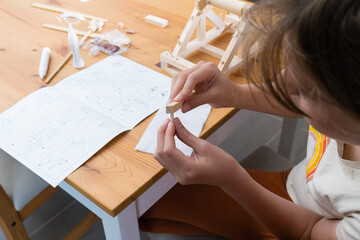 Girl assembling wooden STEM constructor toy.