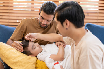 Diversity of a couple man touching the forehead of a sick little boy son at home, caring parent father checking child’s temperature with his hand.