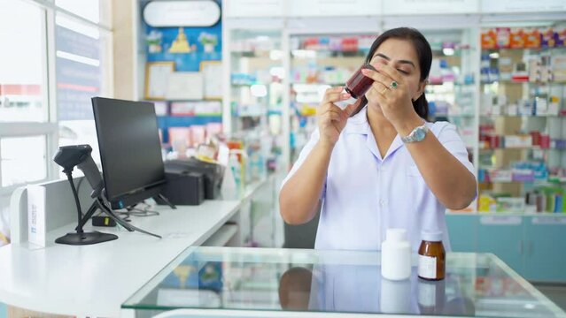 Medical pharmacy and healthcare providers concept. Confident Indian woman pharmacist working inspect medical product, drugs, medicine and supplements in package at cashier counter in modern drugstore.