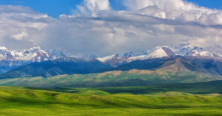Picturesque foothill valley and snow-covered peaks on a spring evening