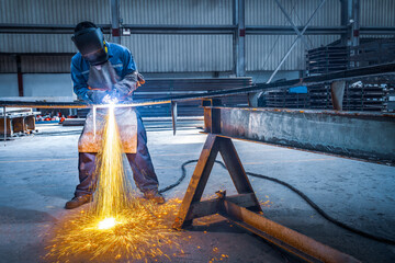 Welder use carbon air arc gouging for hot work cutting or gouging heavy metal steel structure in the fabrication factory.