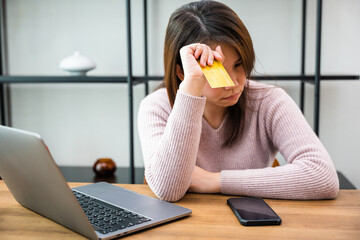 Worried Asian woman having problem with blocked credit card rejected online payment on laptop...