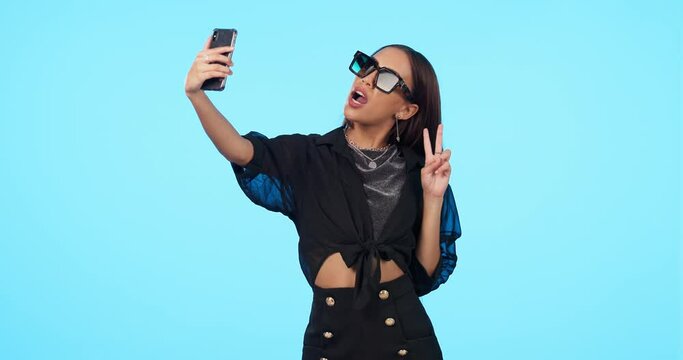 Selfie, sunglasses and woman with peace sign in studio isolated on a blue background mockup. Self photography, v hand gesture and stylish person or influencer with profile picture, fashion and emoji.
