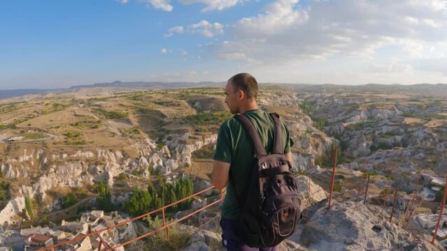 Male photographer captures beautiful mountain scenery while at altitude. Back view of the photographer at work. A man taking pictures as a memento of his trip through Cappadocia