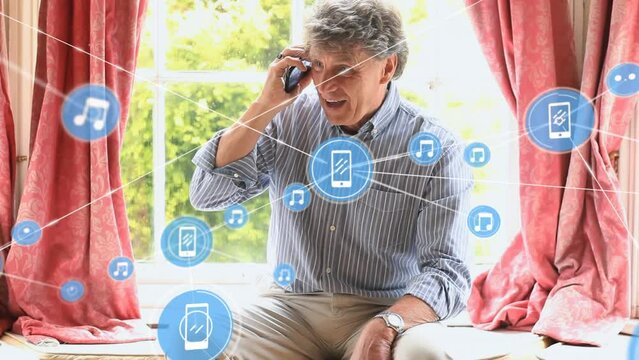 Animation of connected icons over senior caucasian man talking on cellphone at home