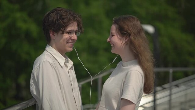 A teenager shares headphones with a girl while listening to their favorite lyric song. first relationship. slow motion video.High quality FullHD video recording