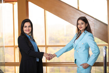 Fototapeta na wymiar Two corporate woman shake hand each other at office.