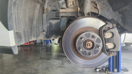 Close-up at car disc brake system during maintenance at the garage. Vehicle equipment object photo, selective focus.