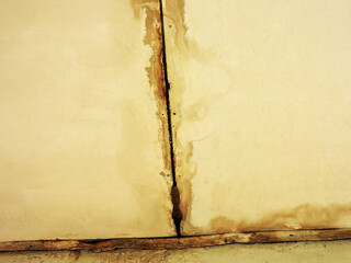 Wet ceiling due to heavy rain. Leaking roof and damp wall. Big wet spots and cracks on the ceiling of the house room 