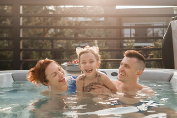 The family is relaxing in their Jacuzzi in the summer outdoors