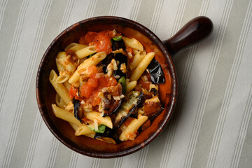 Pasta alla Norma or Penne Rigate with Eggplant and Tomato Sauce and Ricotta in a Rustic Terracotta Bowl - obrazy, fototapety, plakaty