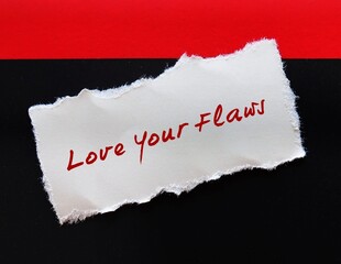Torn note on red black background with handwritten text LOVE YOUR FLAWS, self talk to remind to...
