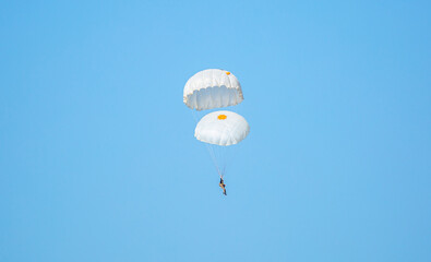 Skydiving. Flying parachutists against the background of the blue sky and mountains. Extreme sport and entertainment.