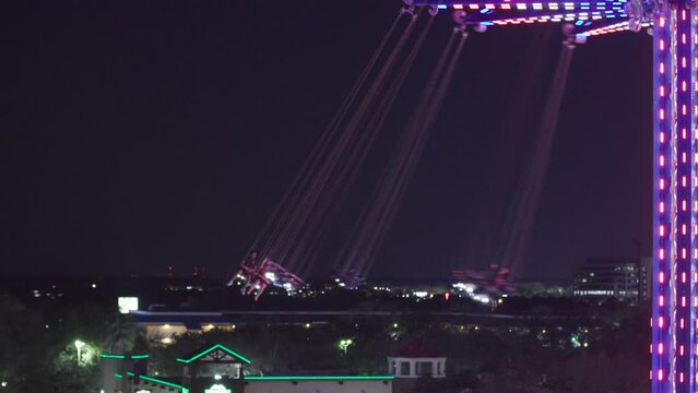 People swinging on a chair swing ride at night at an amusement park in Orlando, Florida.