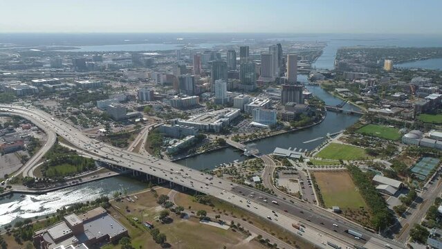 Aerial drone shot of Downtown Tampa skyline descending from a wide  skyline vista approaching buildings and waterfront park during morning traffic
