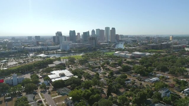 Aerial drone shot of flying over Julian Lane waterfront park toward Downtown Tampa skyline during morning traffic