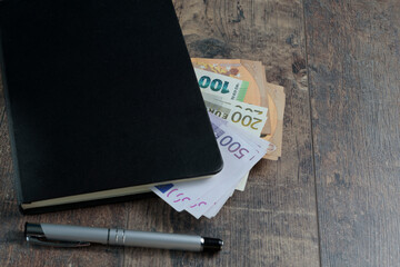 Cash counting, accounting black book, euro banknotes and fountain pen on background.