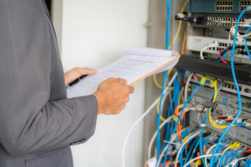 IT administrator technicians take notes and monitor network systems in the server room.