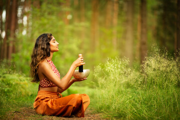 Indian Woman playing Tibetan Singing Bowls with Mallet Outdoors. Relaxing Meditative Music Therapy...